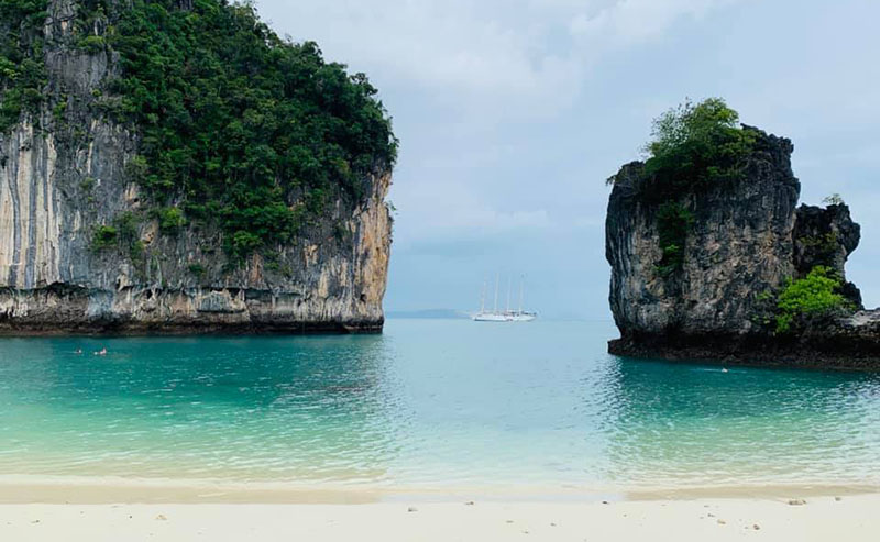 The Star Clipper ship in seen in the distance off a secluded beach in Thailand.