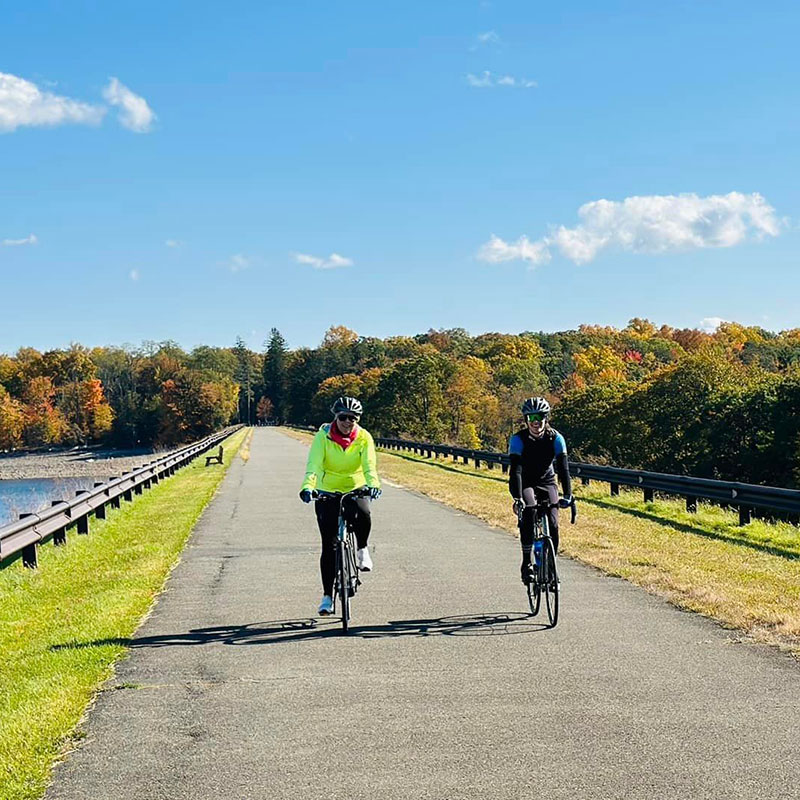 Two cyclists riding next to a lake on a Backroads Cycling Adventure. 