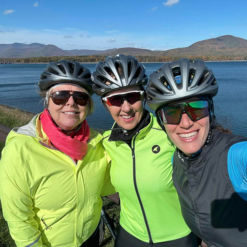 3 cyclists posing in front of lake in upstate New York